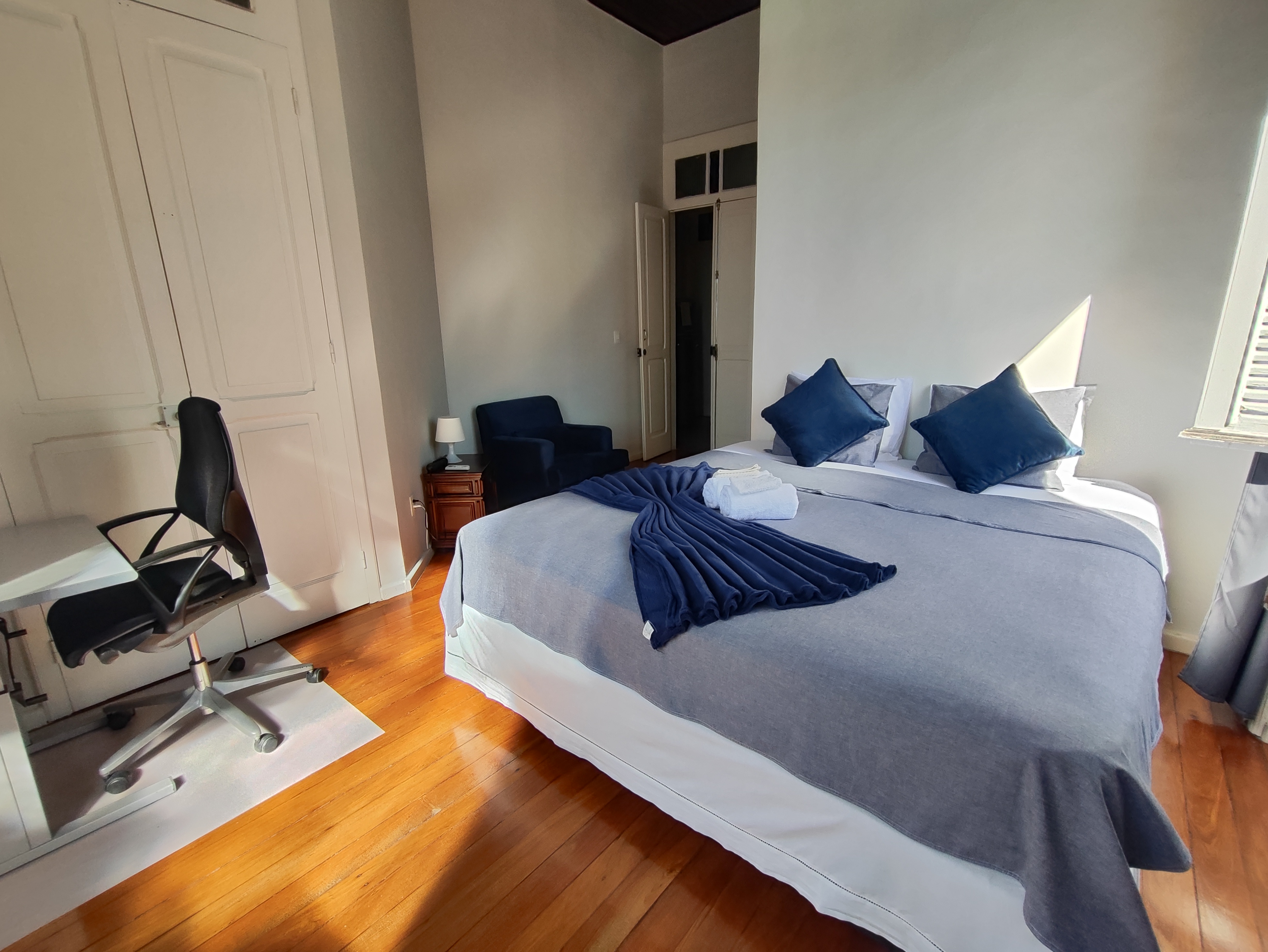 Suíte Tucano da Villa Dourada com cama king, escrivaninha e piso de madeira